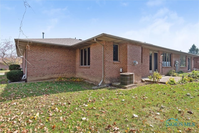 exterior space with central air condition unit and a yard