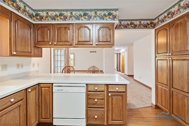 kitchen with light wood-type flooring, white dishwasher, and kitchen peninsula