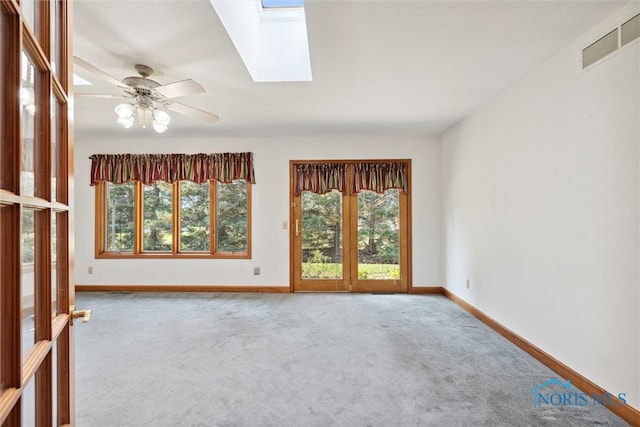 carpeted empty room with ceiling fan and a skylight