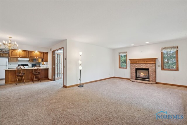 unfurnished living room with light carpet, a wealth of natural light, and a fireplace