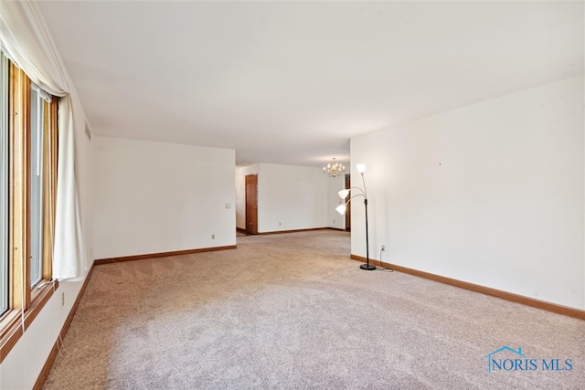 unfurnished room featuring an inviting chandelier and light colored carpet