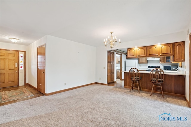 kitchen featuring kitchen peninsula, a breakfast bar, pendant lighting, light colored carpet, and white appliances