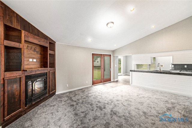 unfurnished living room with sink, carpet flooring, and vaulted ceiling