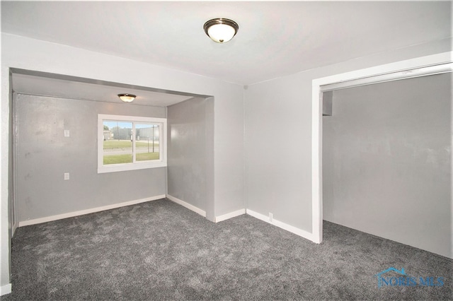 spare room with dark carpet