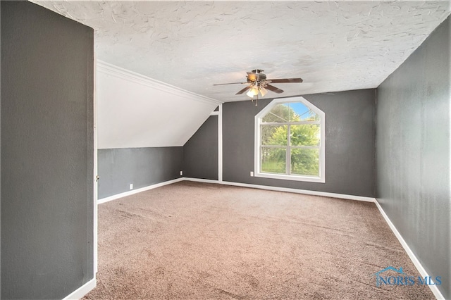 bonus room featuring lofted ceiling, carpet, a textured ceiling, and ceiling fan