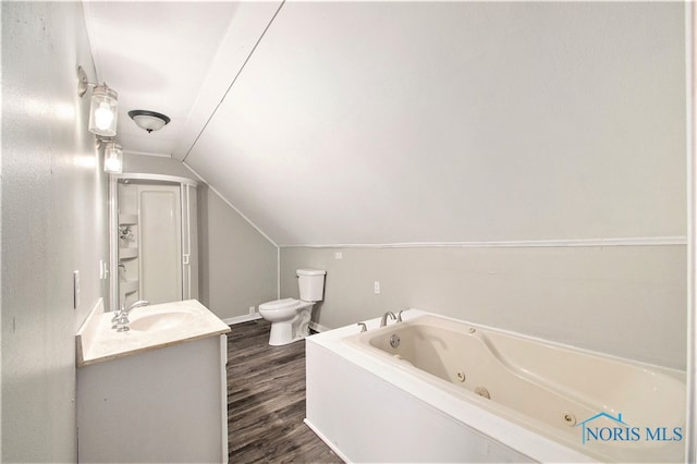 bathroom with toilet, hardwood / wood-style floors, vaulted ceiling, a bathing tub, and vanity