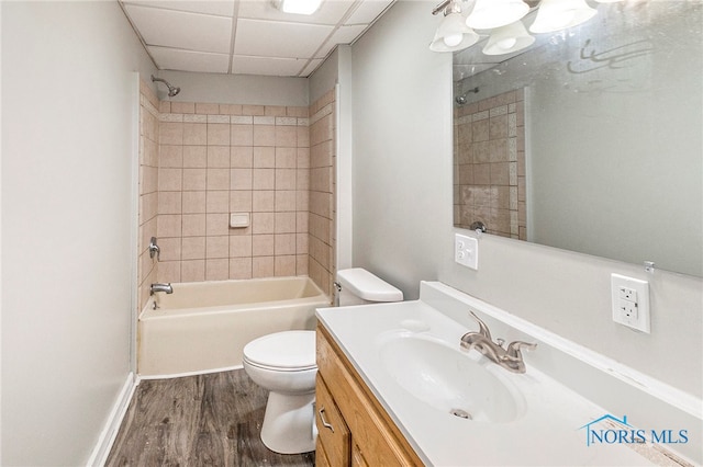 full bathroom featuring toilet, hardwood / wood-style floors, a drop ceiling, tiled shower / bath combo, and vanity