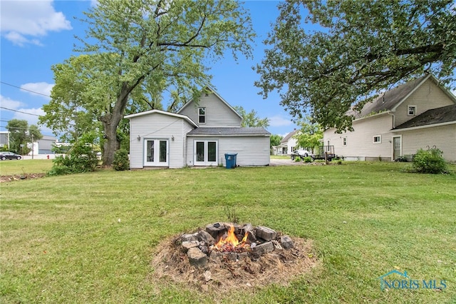 back of property featuring an outdoor fire pit and a lawn