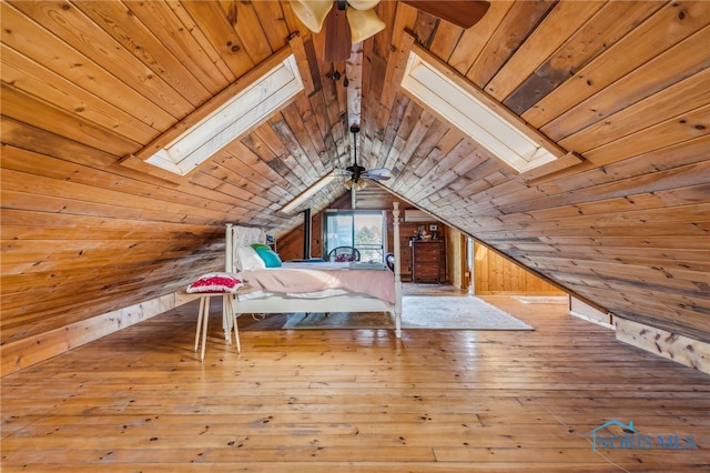 unfurnished bedroom featuring light hardwood / wood-style flooring, lofted ceiling with skylight, wooden walls, and wooden ceiling