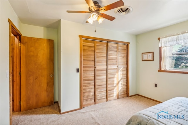 bedroom featuring light colored carpet, a closet, and ceiling fan