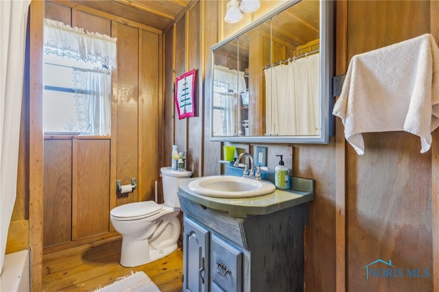 full bathroom with wood walls, separate shower and tub, toilet, vanity, and hardwood / wood-style flooring