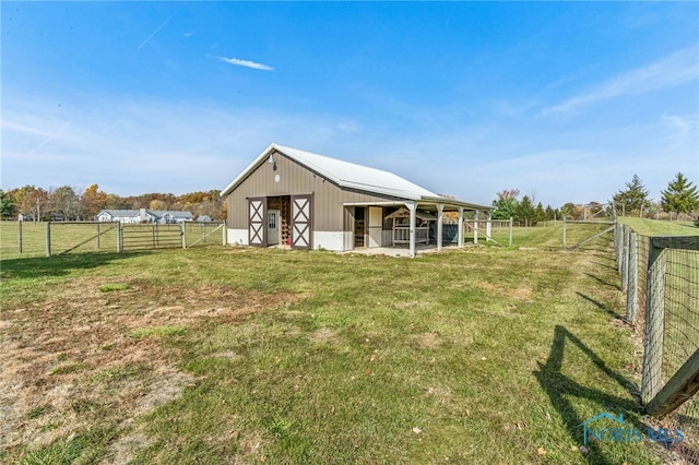 back of property with a rural view and an outdoor structure