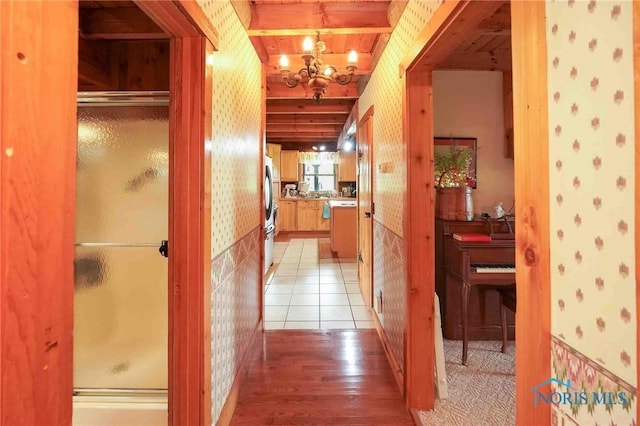 hallway featuring an inviting chandelier, wallpapered walls, and light wood-style flooring