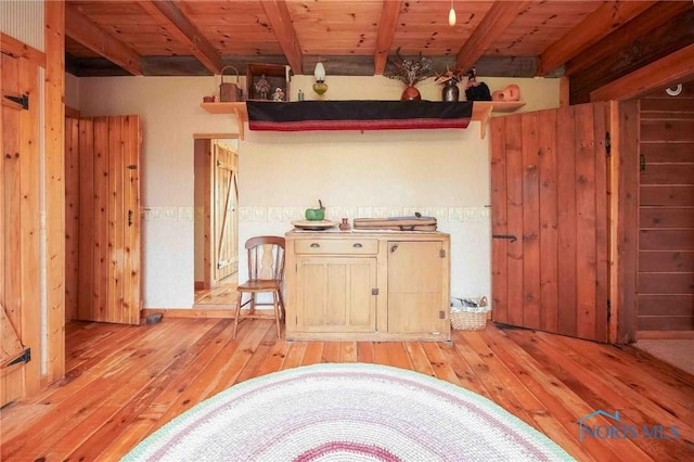 kitchen featuring light wood-style floors, wood walls, wooden ceiling, and beamed ceiling