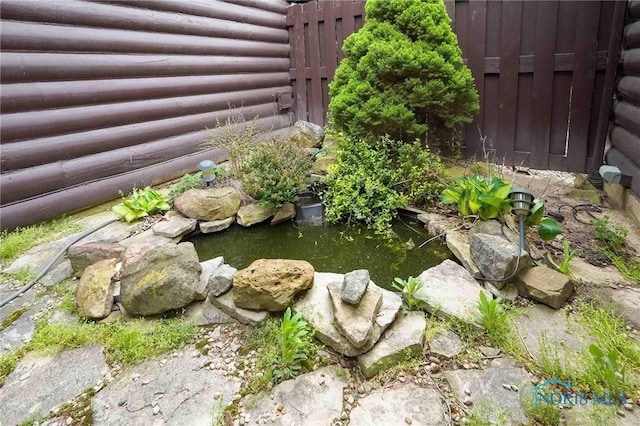 view of yard featuring fence and a small pond