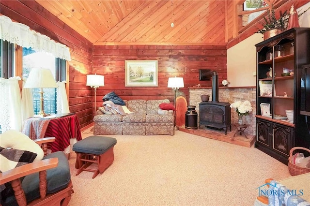 sitting room with wooden walls, a wood stove, carpet floors, vaulted ceiling, and wood ceiling