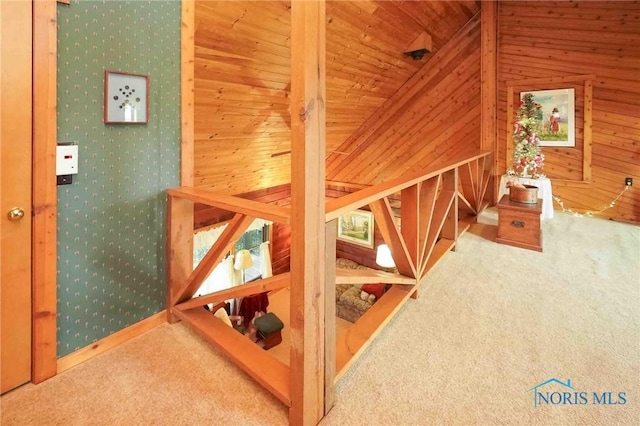 staircase with vaulted ceiling, wallpapered walls, carpet flooring, and wood walls