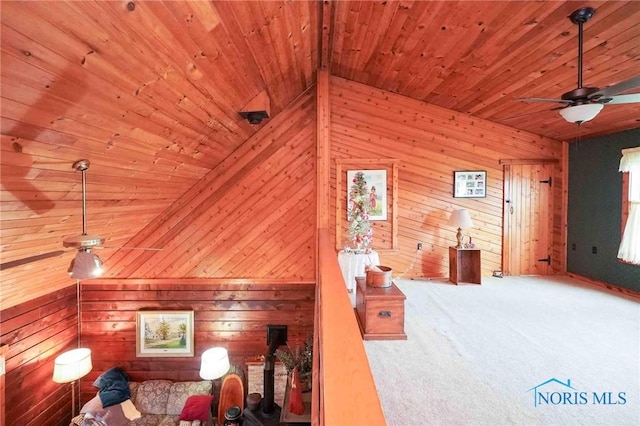 living area with a ceiling fan, wooden walls, wooden ceiling, and carpet flooring