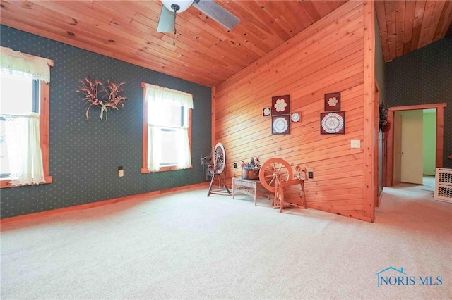 living area with carpet floors, a ceiling fan, wood ceiling, and wallpapered walls