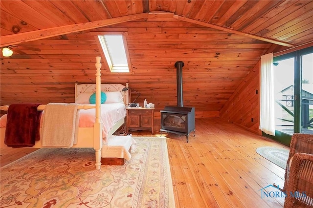 bedroom featuring wood ceiling, a wood stove, vaulted ceiling, light wood finished floors, and wooden walls