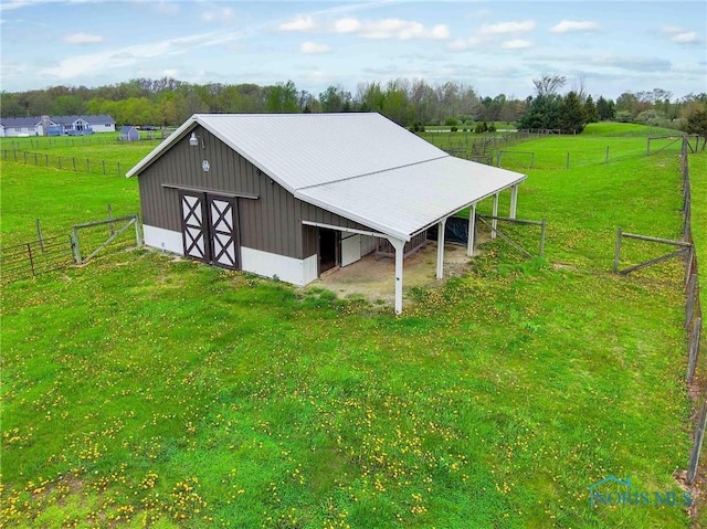 view of outbuilding with fence, an outbuilding, and a rural view