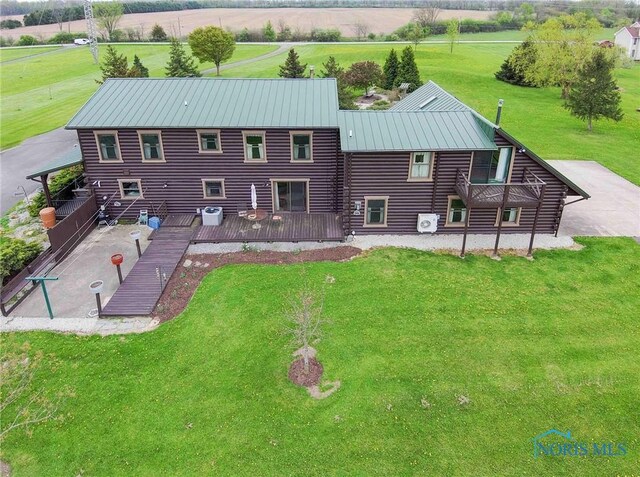 back of property featuring log exterior, a deck, a standing seam roof, a yard, and metal roof