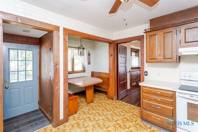 kitchen featuring light hardwood / wood-style flooring, brick wall, pendant lighting, white electric stove, and ceiling fan