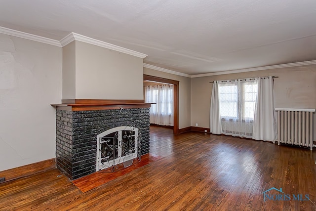 unfurnished living room featuring dark wood-type flooring, crown molding, radiator heating unit, and a brick fireplace