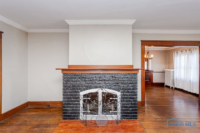 unfurnished living room with ornamental molding, dark hardwood / wood-style flooring, a brick fireplace, and an inviting chandelier