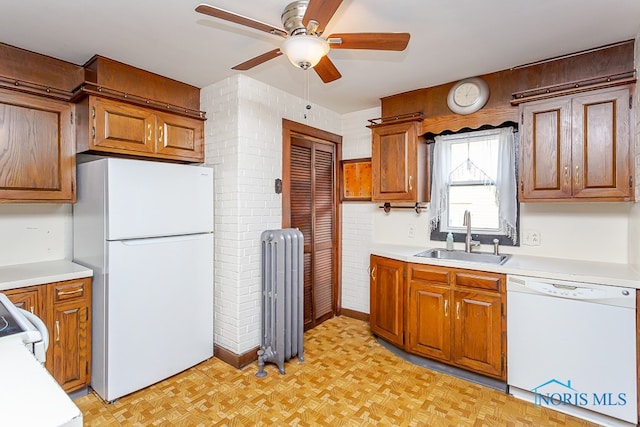 kitchen featuring radiator, white appliances, sink, light parquet flooring, and ceiling fan