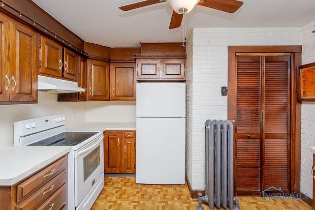 kitchen featuring white appliances, light parquet floors, brick wall, and radiator