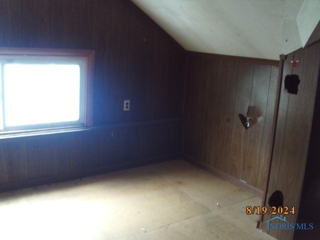 additional living space with wooden walls and vaulted ceiling