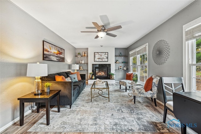 living room featuring ceiling fan, a healthy amount of sunlight, and light wood-type flooring