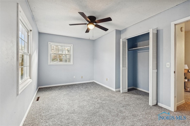 unfurnished bedroom featuring ceiling fan, a textured ceiling, carpet flooring, and a closet