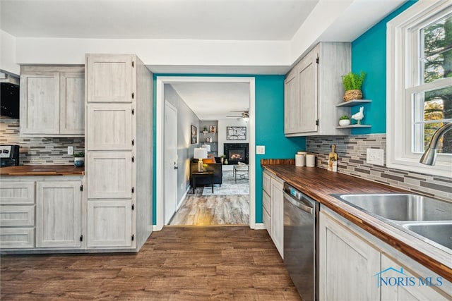 kitchen with dark wood-type flooring, butcher block countertops, stainless steel dishwasher, and plenty of natural light