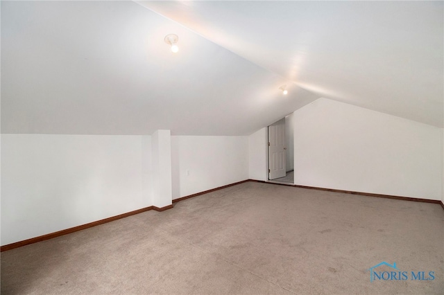 additional living space with vaulted ceiling and light carpet