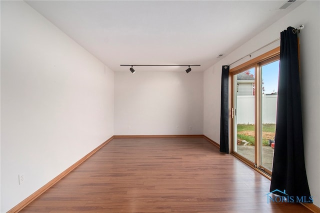 unfurnished room featuring hardwood / wood-style floors and rail lighting