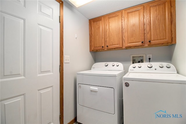 laundry room with cabinets, a textured ceiling, and separate washer and dryer