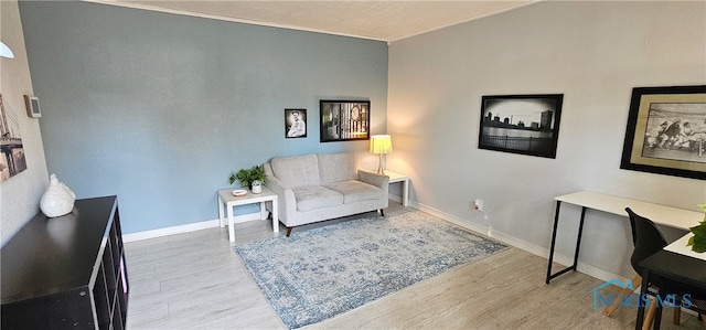 sitting room with ornamental molding and light wood-type flooring