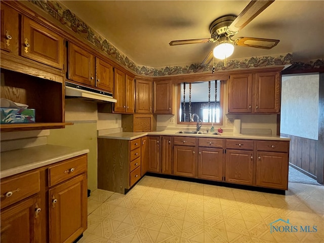 kitchen featuring ceiling fan, wood walls, and sink