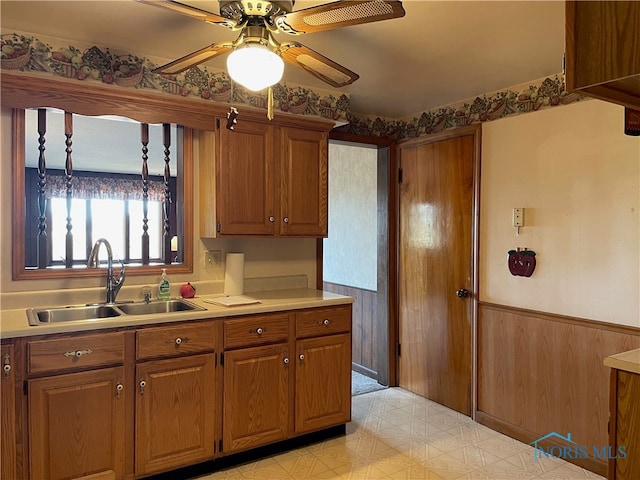 kitchen with ceiling fan, wood walls, and sink