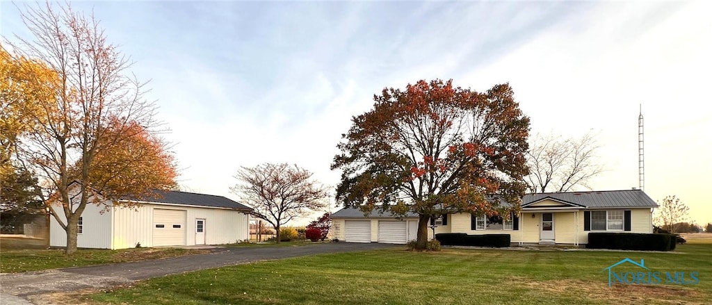 ranch-style home with an outdoor structure, a front yard, and a garage