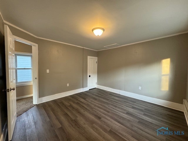 unfurnished room featuring ornamental molding and dark hardwood / wood-style floors