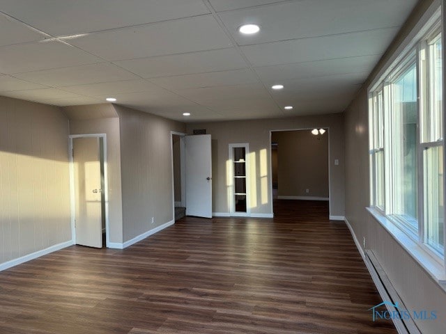 spare room with dark wood-type flooring, a paneled ceiling, and a baseboard radiator