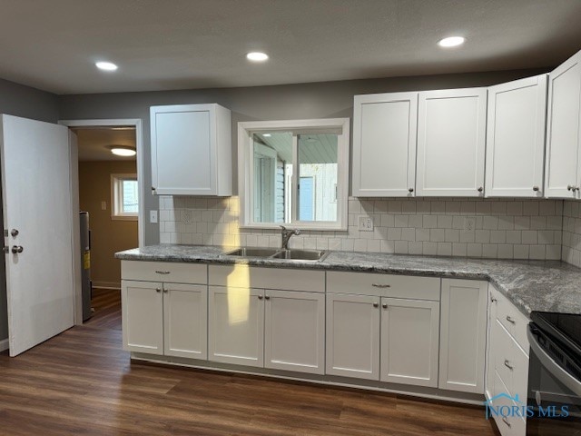 kitchen featuring light stone countertops, sink, white cabinetry, and dark hardwood / wood-style floors