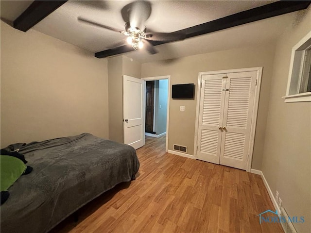 bedroom with ceiling fan, a closet, beamed ceiling, and light hardwood / wood-style floors