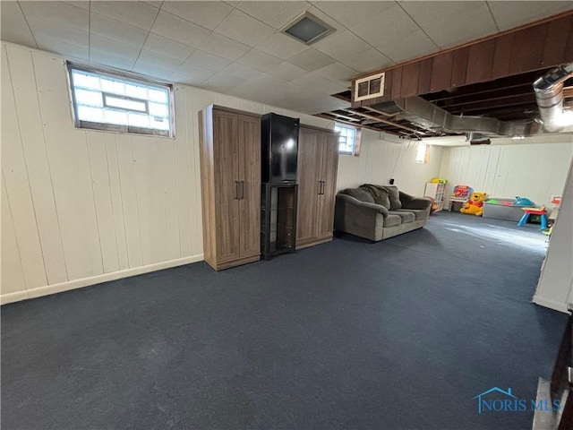 basement with a wealth of natural light and dark colored carpet