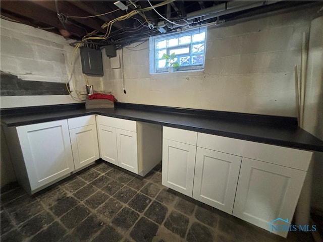 interior space with white cabinetry and electric panel