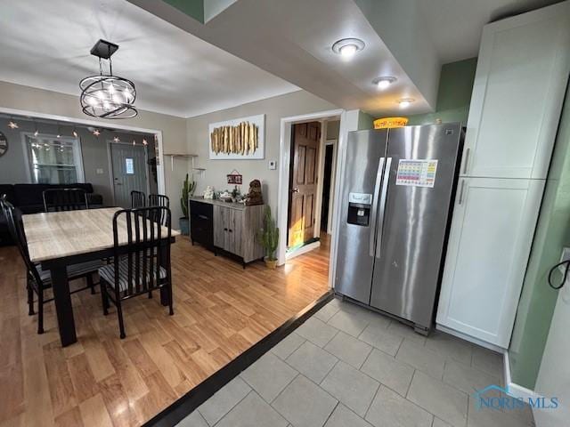 dining area with light wood-type flooring and an inviting chandelier