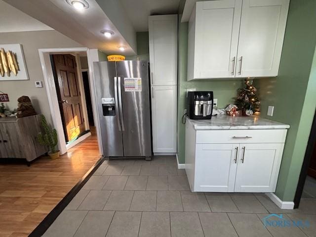 kitchen with light tile patterned floors, white cabinets, and stainless steel fridge